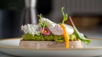 A dish with poached eggs, avocado, and greens on a slice of bread.