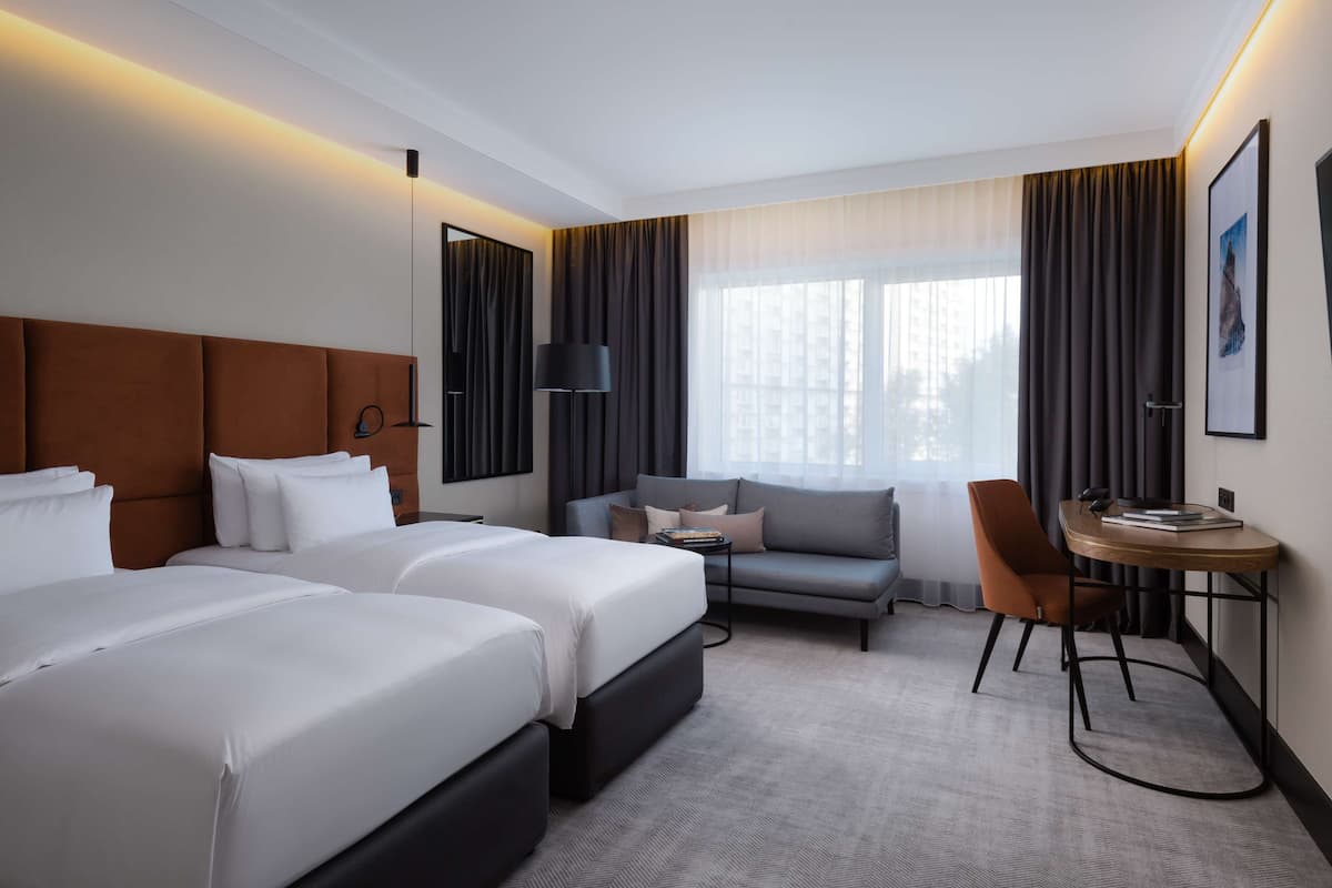 Habitación de hotel con dos camas, un sofá, un escritorio y una silla.
