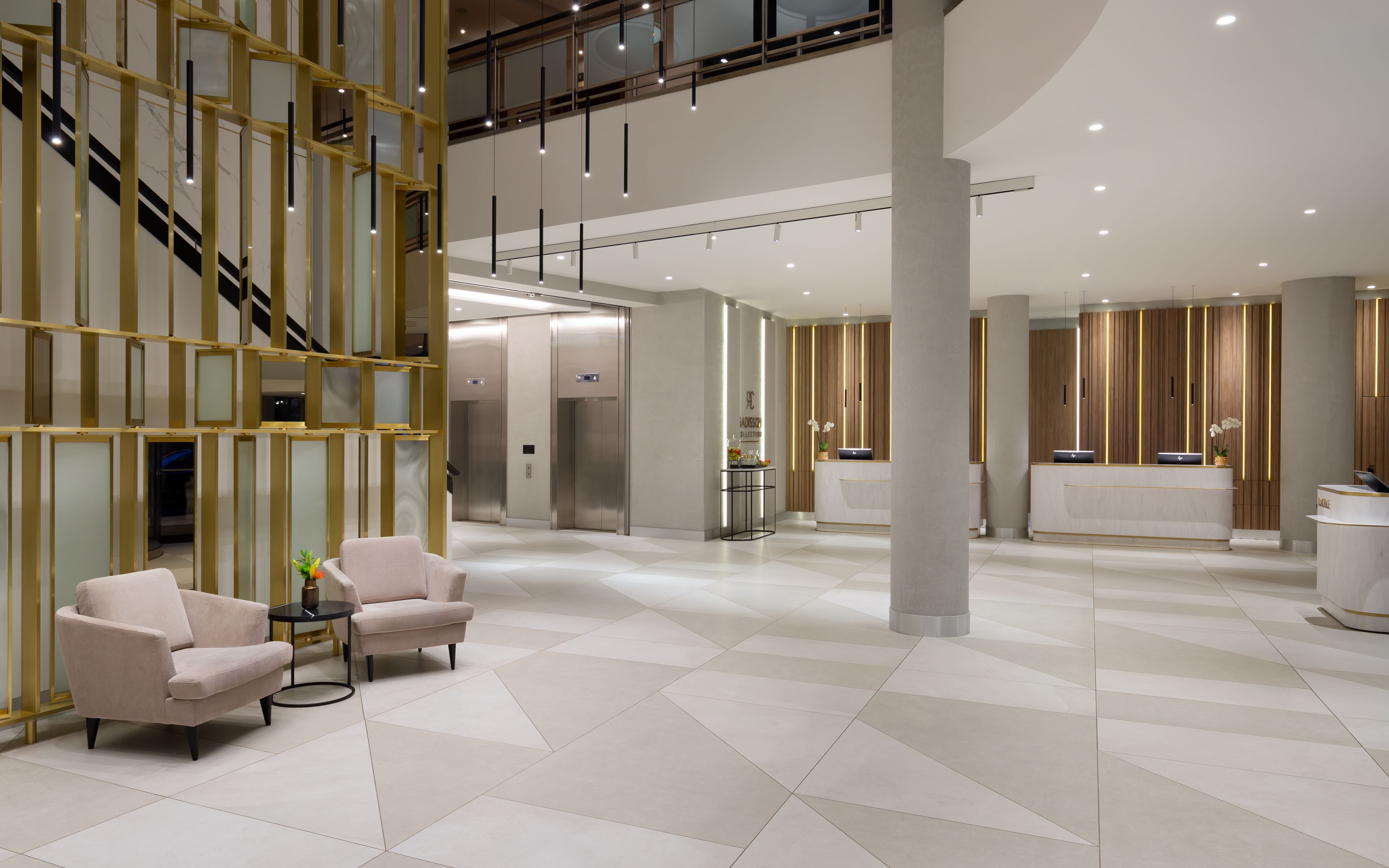 A spacious lobby with a modern design, featuring a reception desk, seating area, and an elevator.