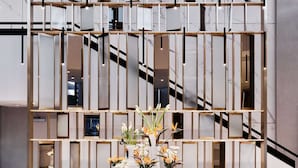 A modern interior with a central staircase, a decorative wall with mirrors, and a round table with flowers. - Radisson Collection Hotel, Warsaw (Warsaw)
