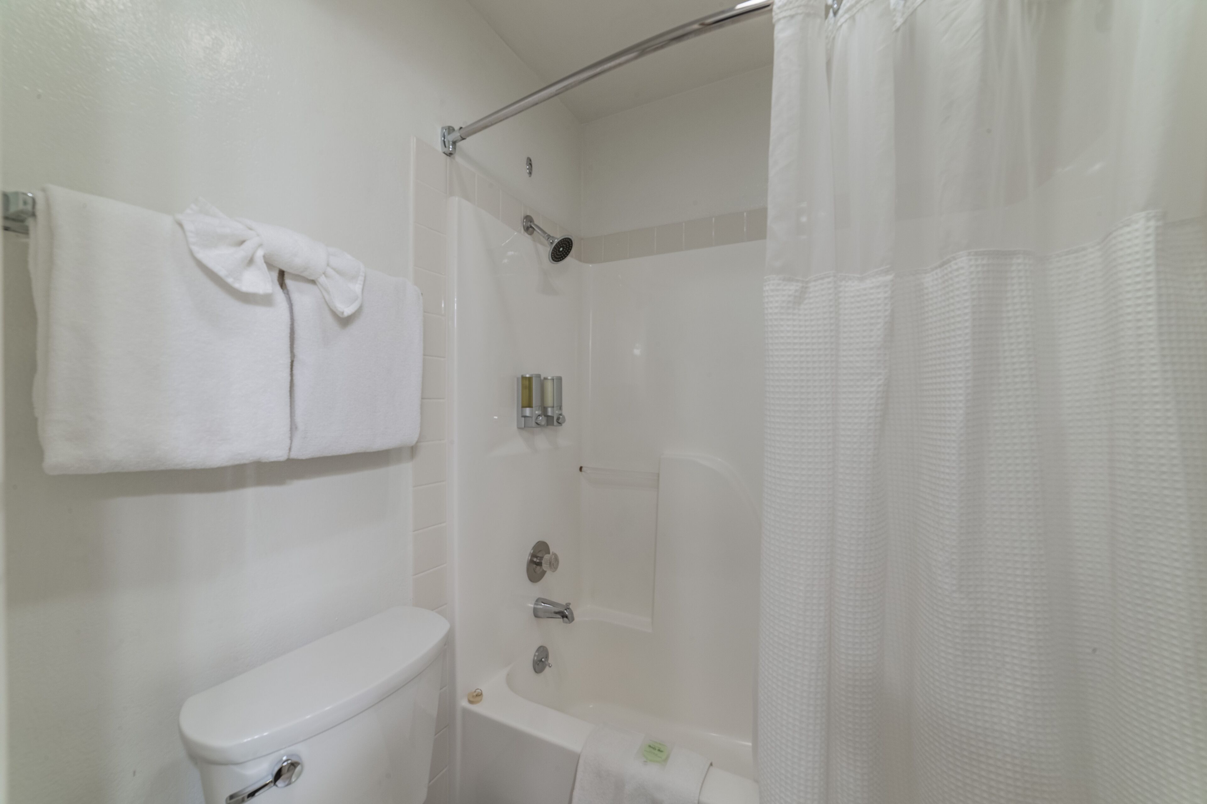 Un baño con inodoro, bañera, ducha y un perchero con dos toallas.
