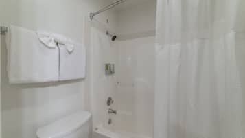 A bathroom with a toilet, a bathtub, a shower, and a towel rack with two towels.