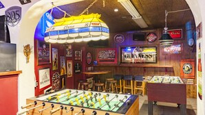 Una habitación con mesa de fútbol, barra y varios recuerdos en las paredes.