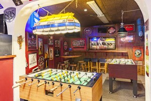 A room with a foosball table, a bar area, and various memorabilia on the walls.