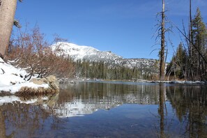 A tranquil lake surrounded by snow-covered mountains and leafless trees. - Alpenhof Lodge (Mammoth Lakes)