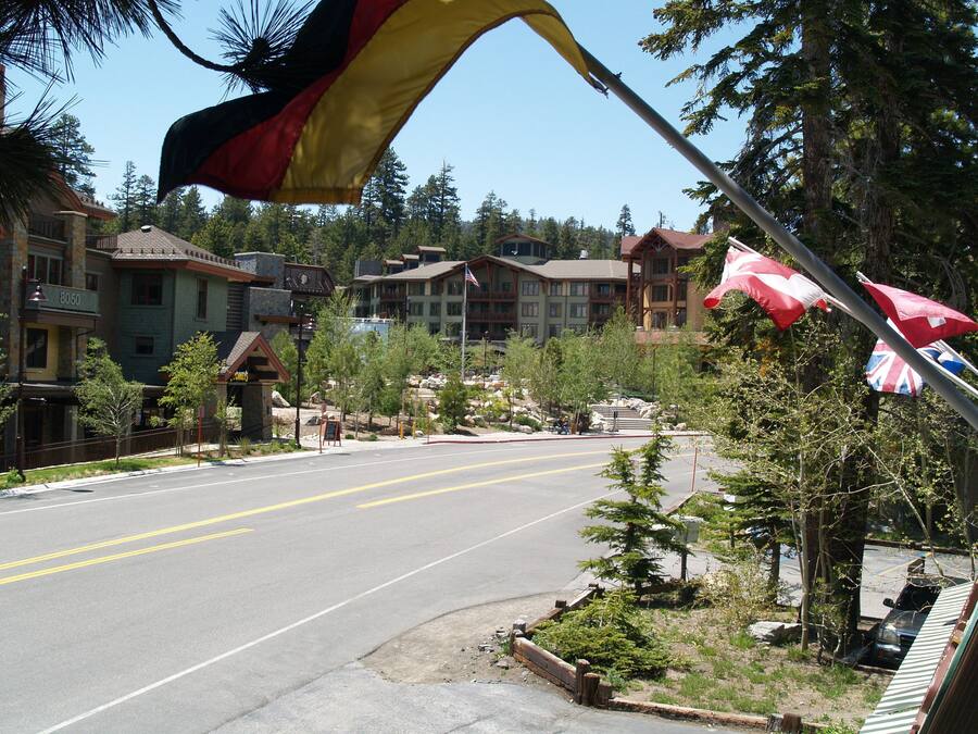 Un hotel con una bandiera ben visibile, una strada e alberi circostanti.