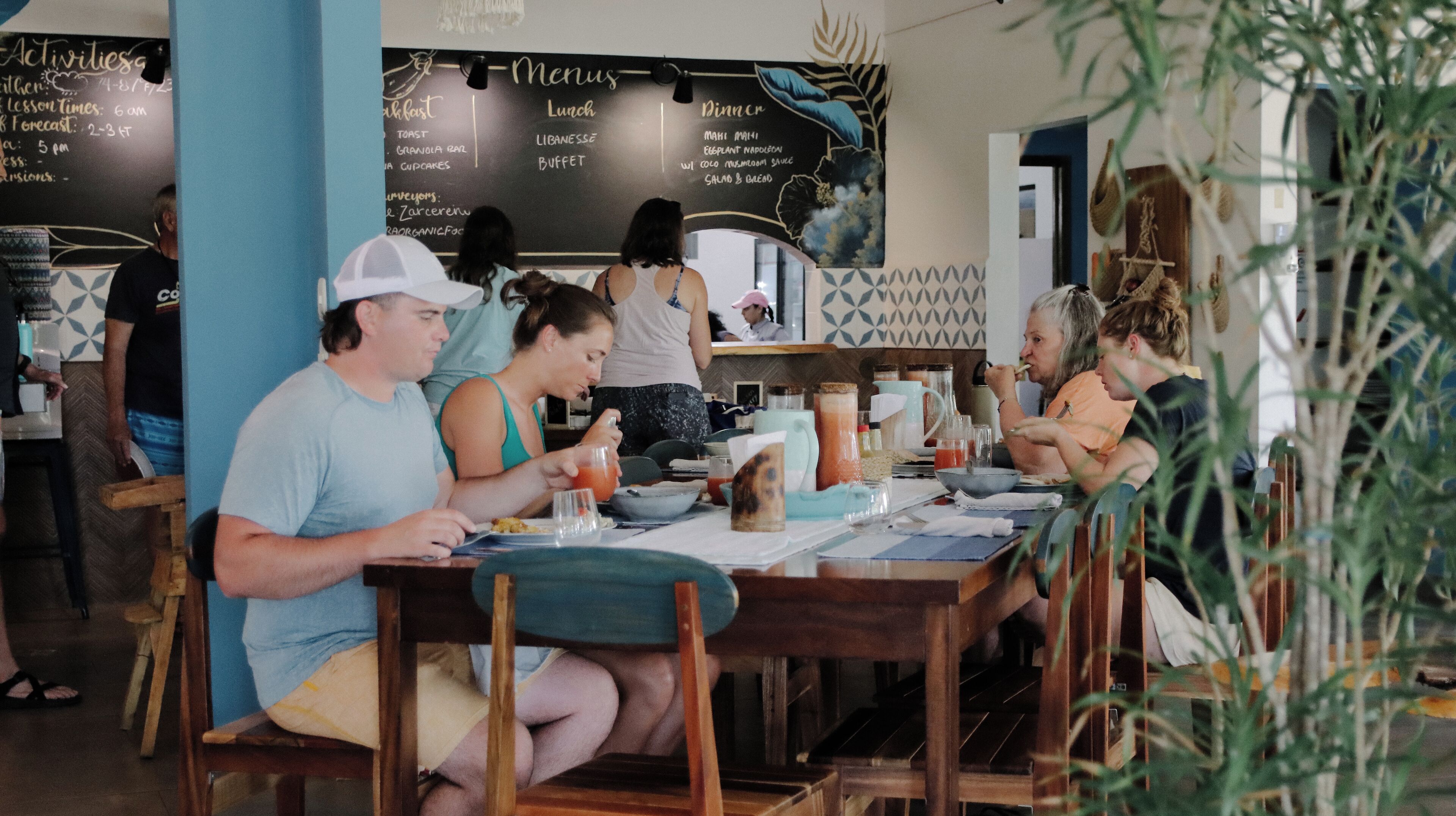 Un restaurante con un menú en la pizarra que anuncia opciones para desayuno, almuerzo y cena.