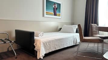 Una habitación de hotel con cama, una silla, un escritorio, un cuadro en la pared y una ventana con cortinas.