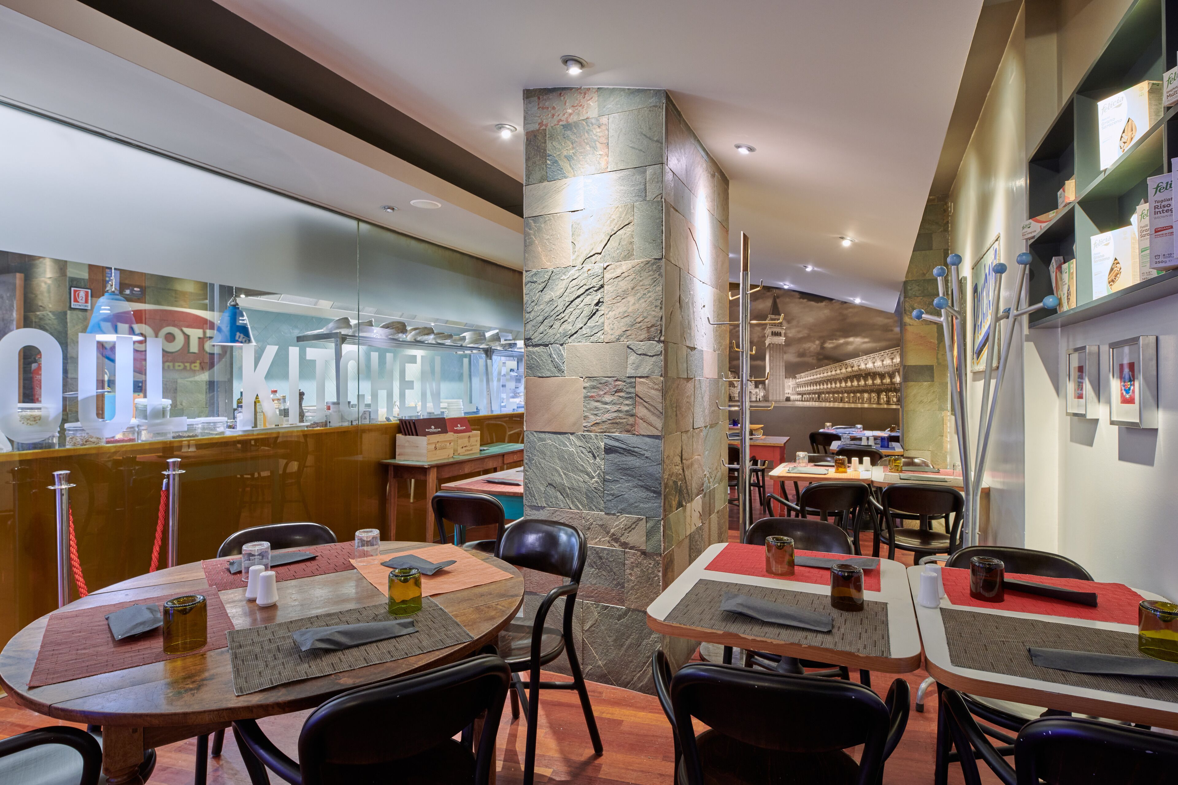 Un restaurante con pilares de piedra, mesas de madera y sillas negras.