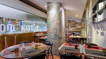 Un restaurante con pilares de piedra, mesas de madera y sillas negras.