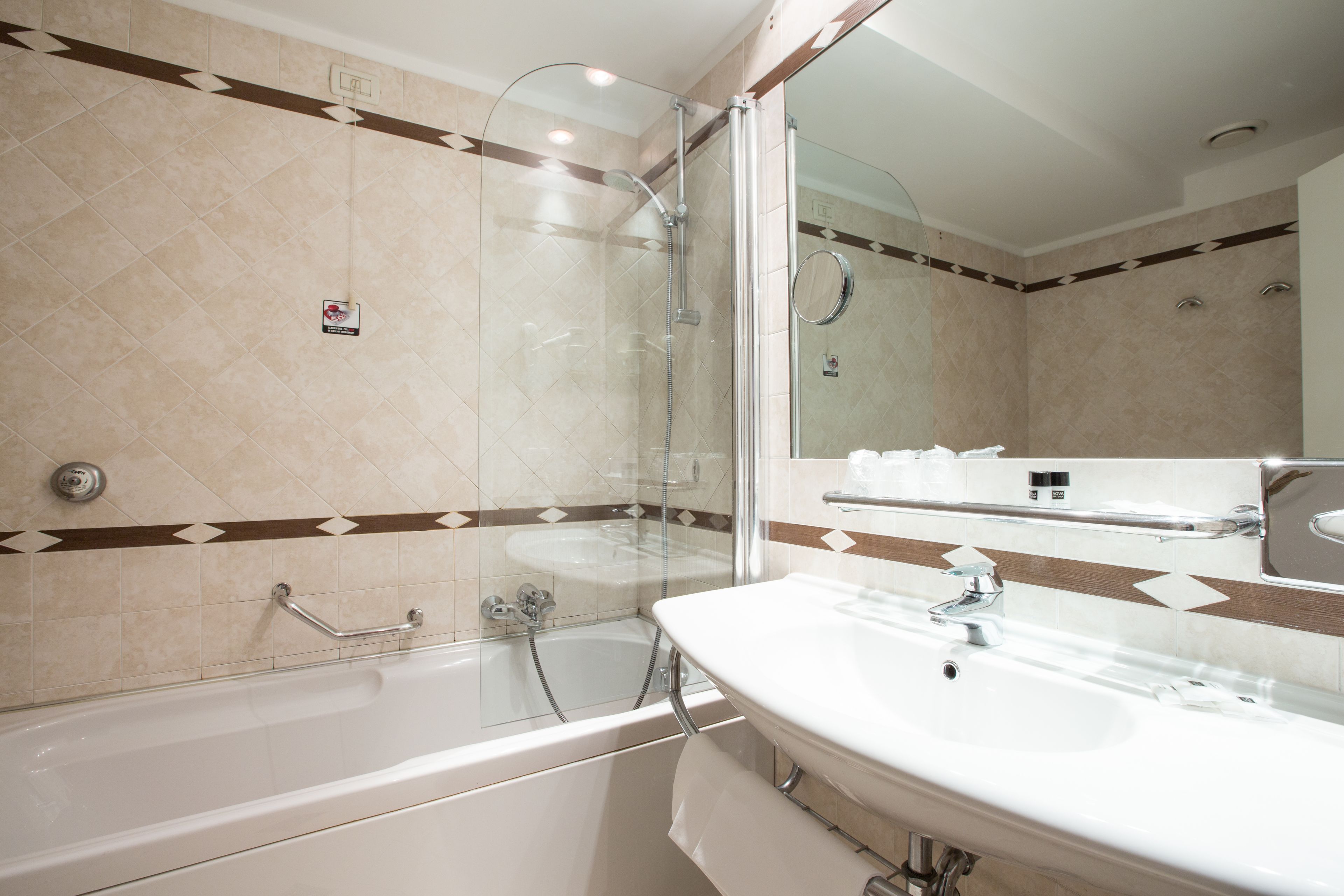 A modern bathroom with a glass-enclosed shower, a white bathtub, and a large mirror above a sink.
