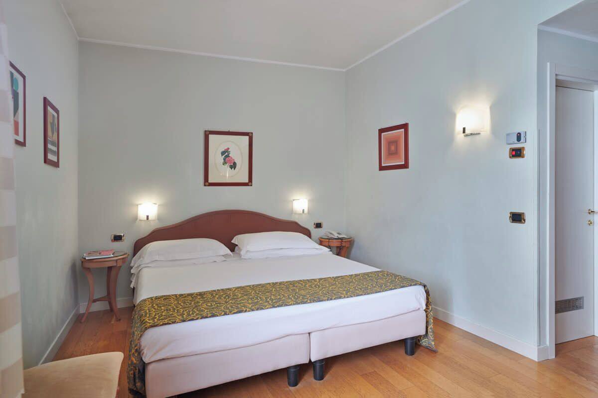 Une chambre d’hôtel bien aménagée, avec un grand lit, des tables de chevet et des tableaux encadrés aux murs.