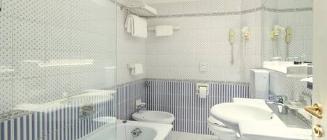 A bathroom with a bathtub, toilet, and sink, featuring blue and white striped tiles and a mirror.