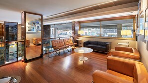 A modern living room with leather sofas, a glass partition, and a large window offering a city view. - Hotel Plaza Venice (Mestre)