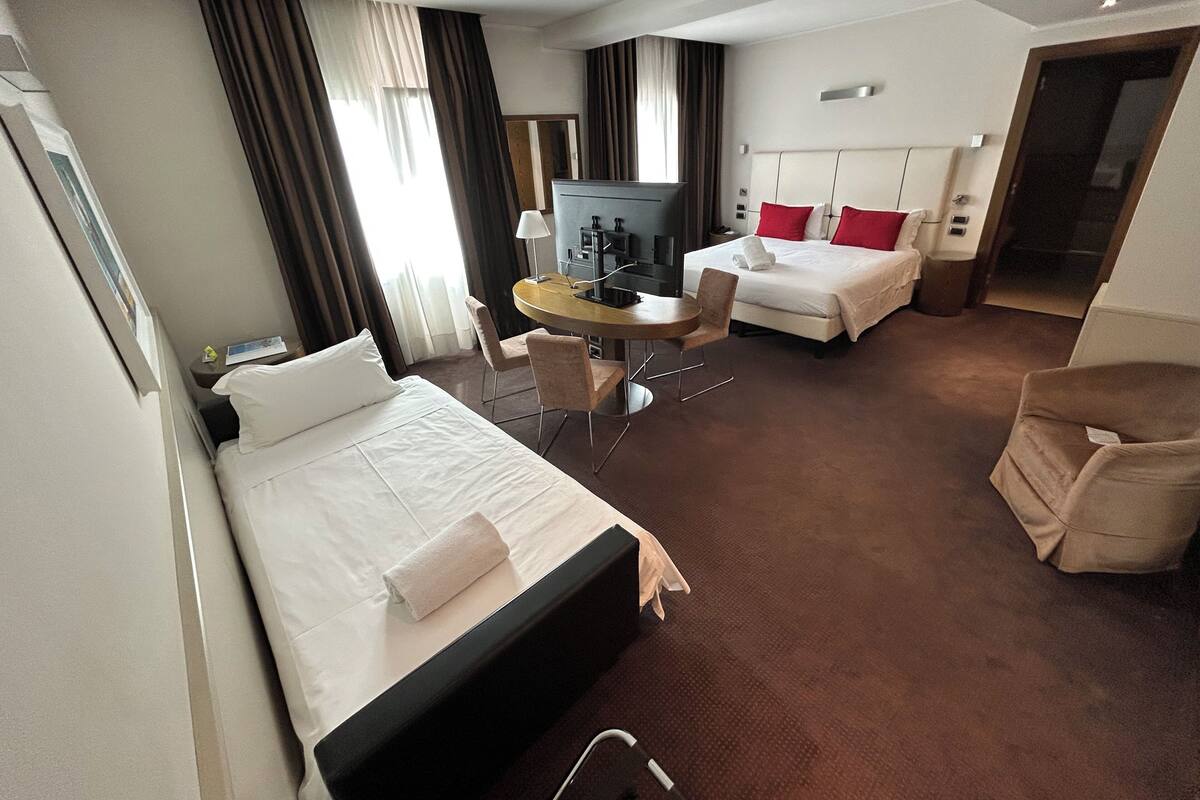 Une chambre d’hôtel avec deux lits, un bureau, une chaise, une télévision et une salle de bain.