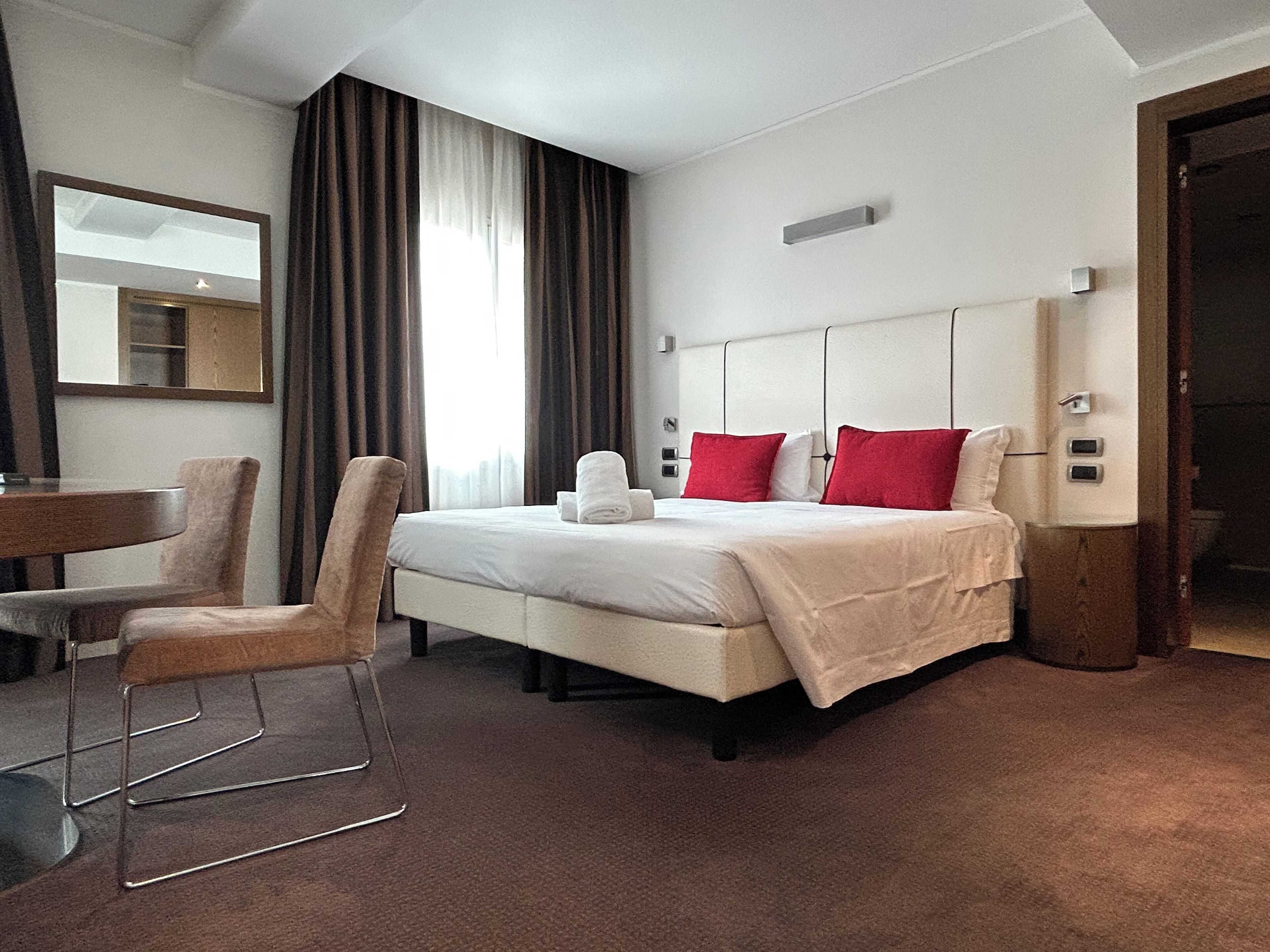 Une chambre d’hôtel avec un lit, une chaise, un bureau et un miroir.