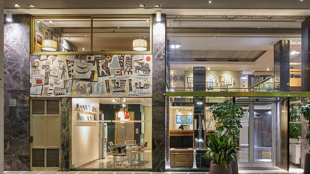 A hotel lobby with a marble floor, a reception desk, and a seating area with chairs and tables. - Hotel Plaza Venice (Mestre)