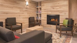 A cozy living room with a fireplace, wooden walls, and a bookshelf.