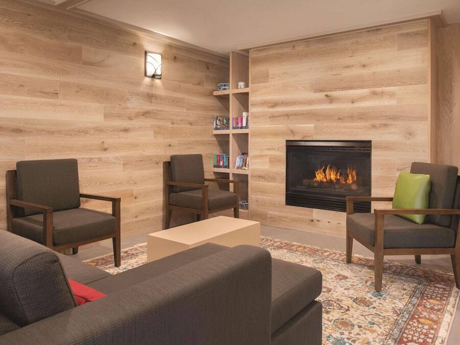 A cozy living room with a fireplace, wooden walls, and a bookshelf.