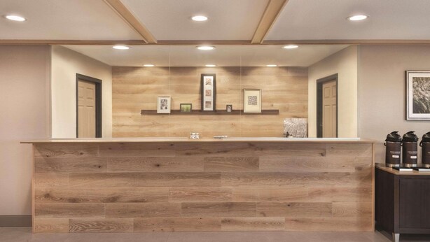A reception desk with a wooden finish, framed pictures above it, and a set of black containers on the right.