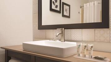 A bathroom with a white sink, a mirror, and two framed botanical prints on the wall.