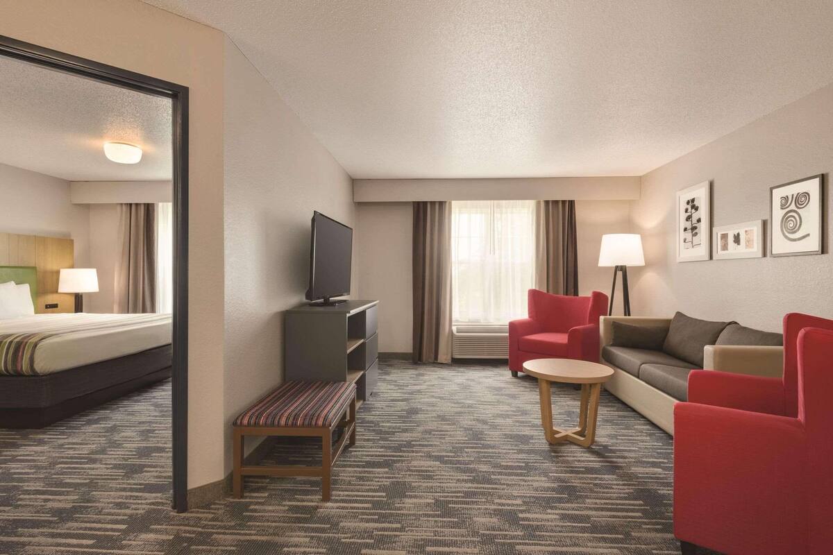 A hotel room with a bed, a TV, a desk, a chair, a sofa, and a small table.