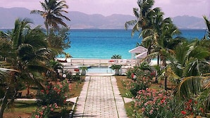 A pathway leading to a pool with a view of the ocean and mountains in the background.