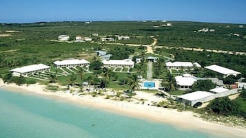 Une vue aérienne d’un complexe hôtelier comprenant plusieurs bâtiments, une tour centrale et une plage.