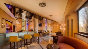 Um hall de hotel moderno com área de bar, assentos e grandes janelas.