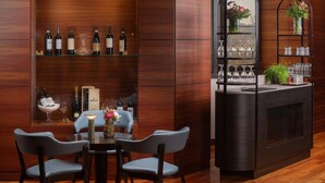 Uma área de bar com painéis de madeira, garrafas de vinho, copos e um balcão com uma planta.