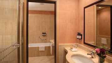 Un baño moderno con ducha de vidrio, bañera y lavabo con espejo.