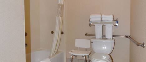 A bathroom with a bathtub, toilet, and a small chair.