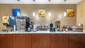 Une cuisine d’hôtel équipée d’une machine à café, d’un coin pour préparer le thé et d’un réfrigérateur.