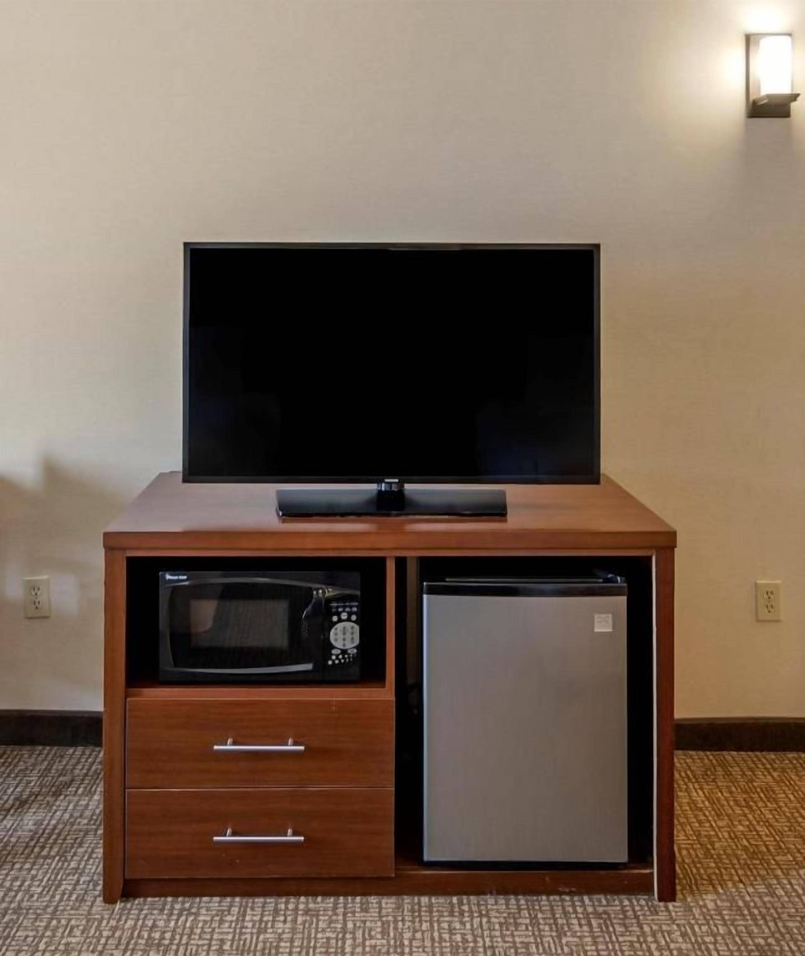 Een houten kast met een televisie, magnetron en koelkast.