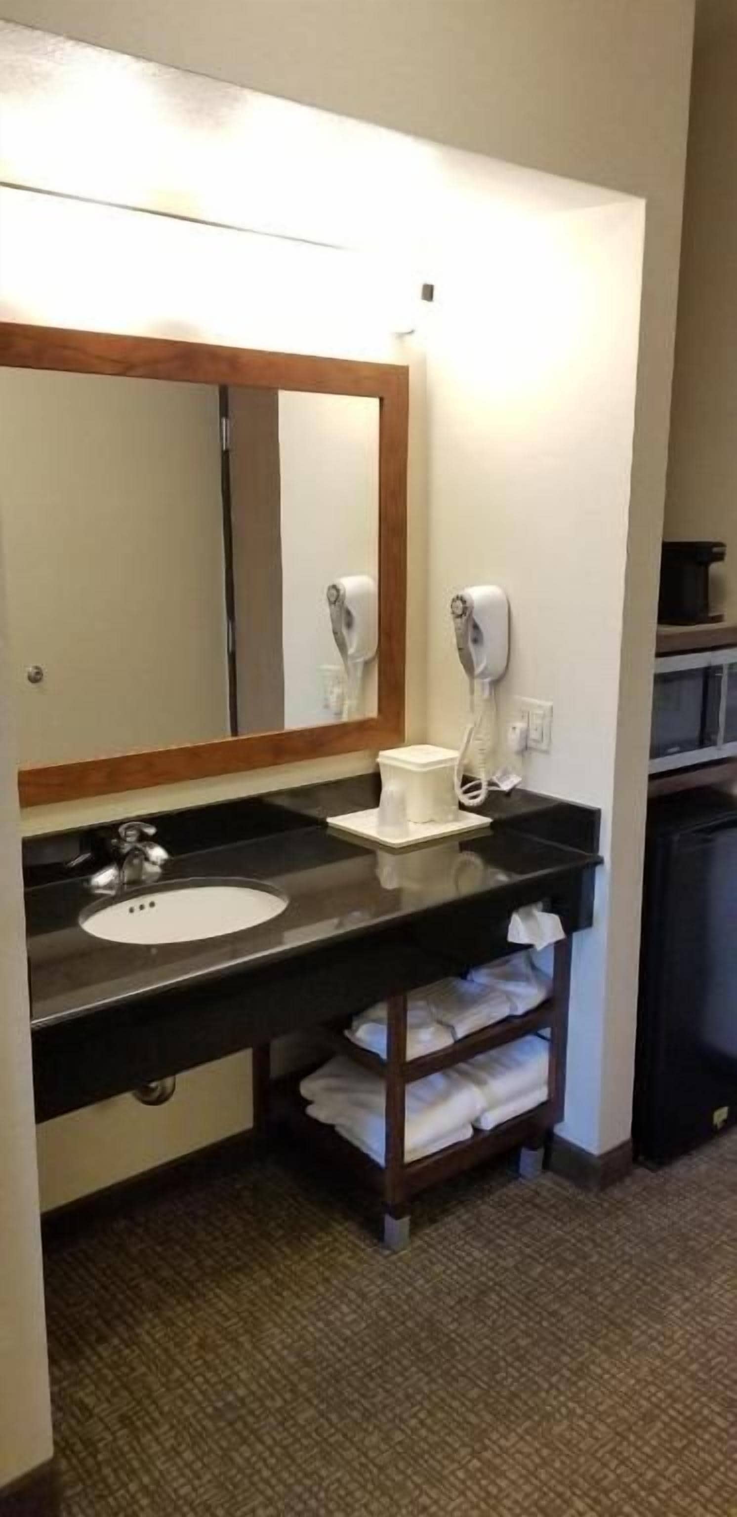 A hotel bathroom with a sink, mirror, towel rack, and hairdryer.