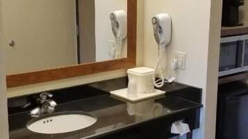 A hotel bathroom with a sink, mirror, towel rack, and hairdryer.