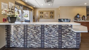 Un espace d’accueil doté d’un comptoir carrelé, d’un extincteur, d’une fenêtre offrant une vue agréable et d’un distributeur de café fixé au mur.