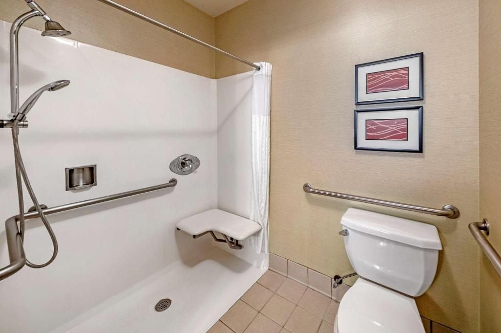 Un baño con ducha, inodoro y un estante pequeño.