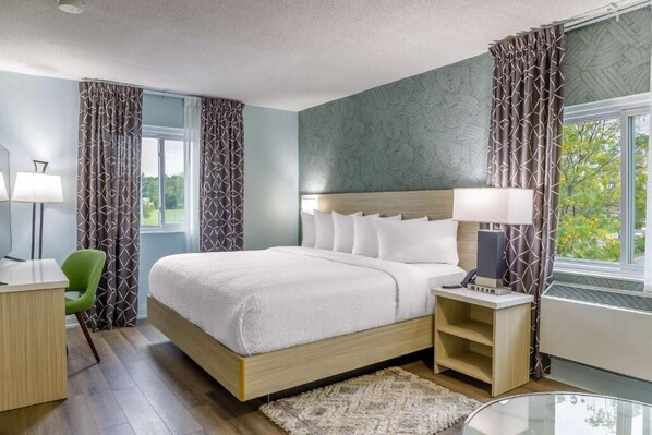 A modern hotel room with a large bed, bedside tables, a desk, and a chair. - Mammas Inn (Niagara Falls)