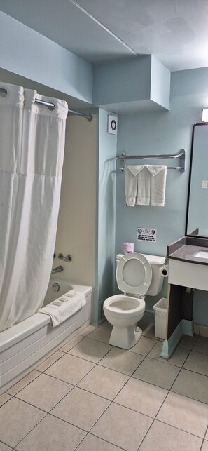 A bathroom with a bathtub, toilet, and sink. - Mammas Inn (Niagara Falls)