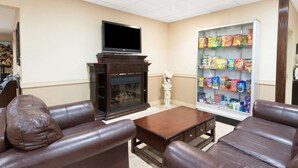 Een woonkamer met een open haard, leren banken, een salontafel, een flatscreen televisie en een minibar.