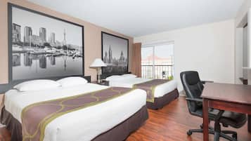 A hotel room with two beds, a desk, a chair, and large framed cityscape pictures on the wall.