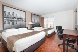 A hotel room with two beds, a desk, a chair, and large framed cityscape pictures on the wall.