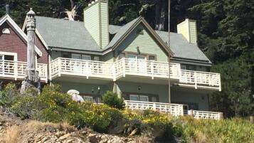 A two-story house with a green roof and white balcony railings.