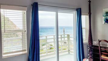 Un dormitorio con una cama grande, vista al océano y un balcón con barandilla.