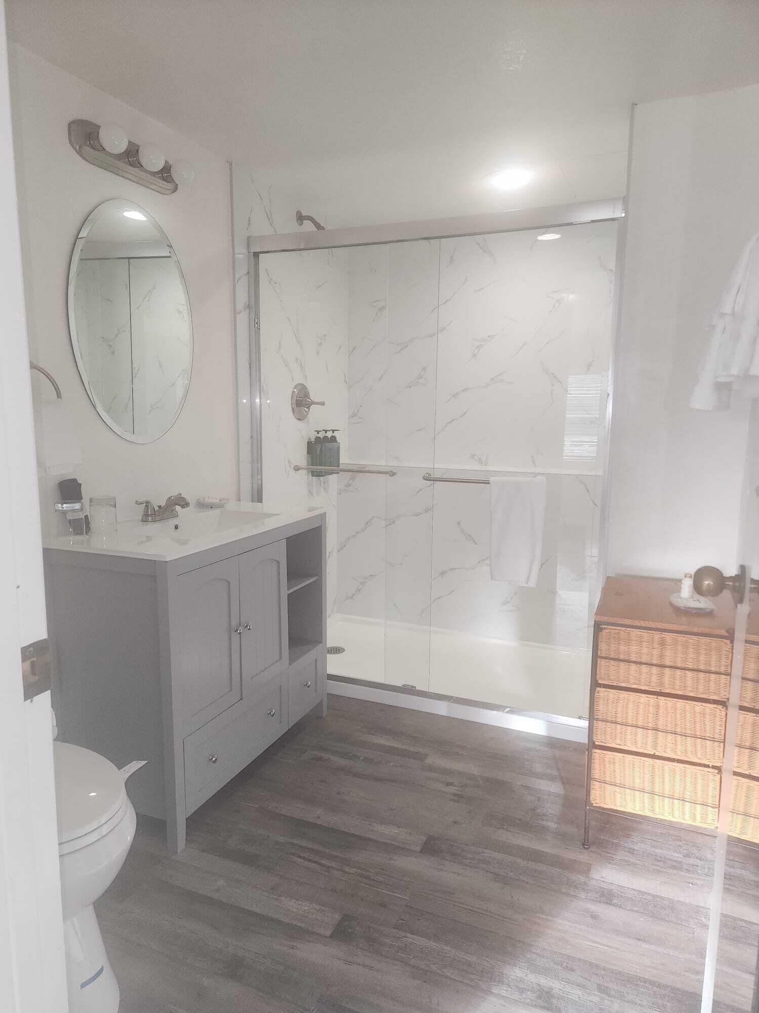 A modern bathroom with a glass-enclosed shower, a vanity with a mirror, and a toilet.