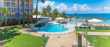 Una piscina al aire libre, sombrillas, sillones reclinables de piscina