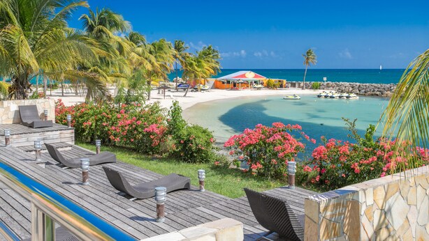 Een resort aan het strand met ligbedden, een zwembad en uitzicht op de oceaan.