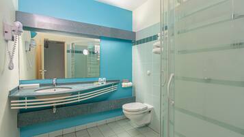 Een badkamer met een blauwe accentmuur, een wastafel met een marmeren aanrechtblad, een toilet en een douchecabine met glazen wanden.