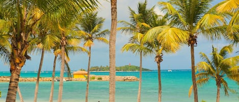 Na praia, areia branca, espreguiçadeiras, guarda-sóis 